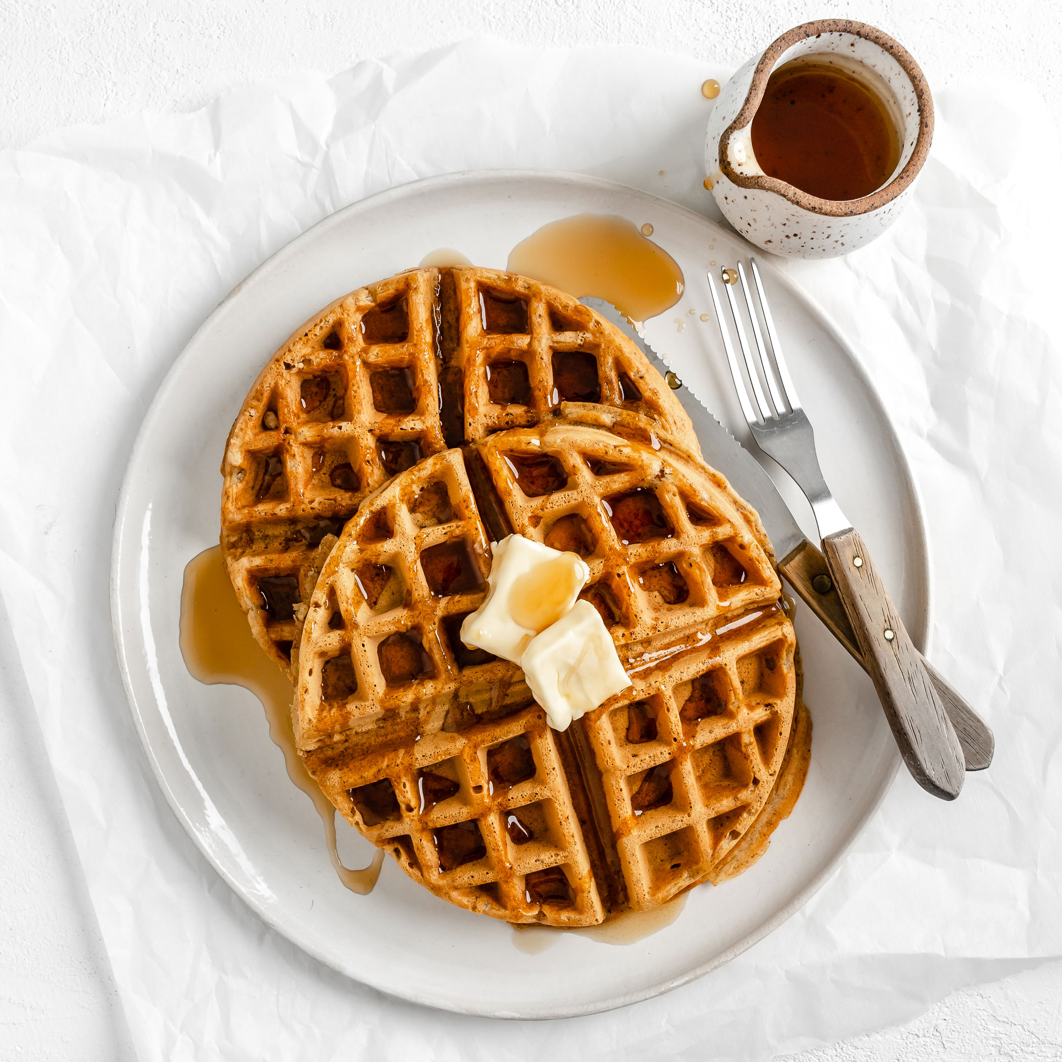 Photos of two vegan waffles on plate with butter and syrup