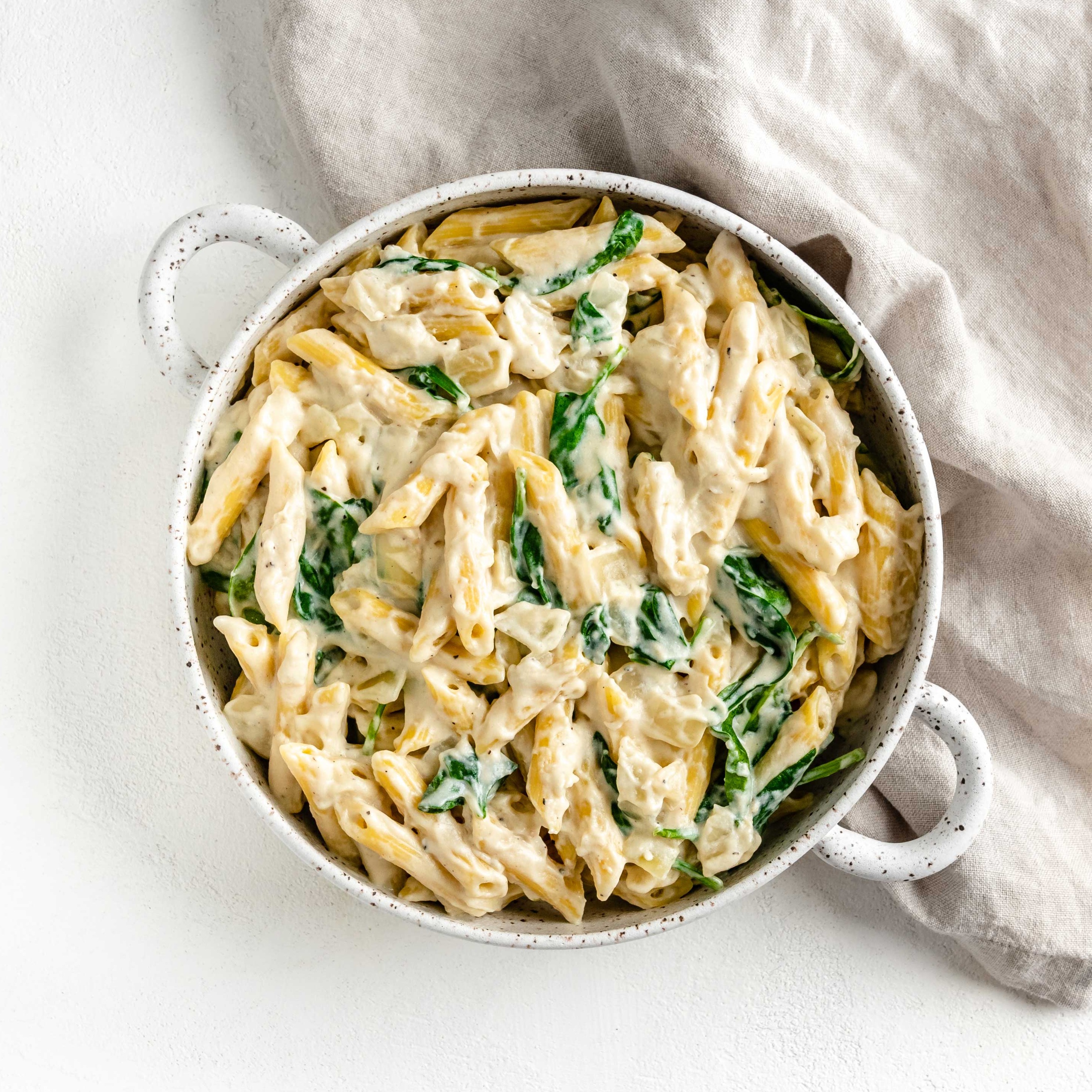 Bowl of penne pasta and spinach with alfredo sauce